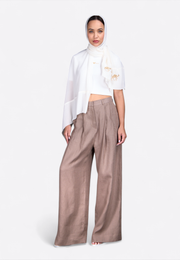 Front view of beige wide-leg linen trousers on model, East Vibe